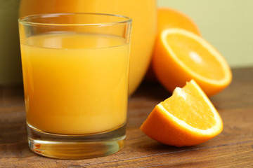 a glass of orange juice on a brown wooden background with orange