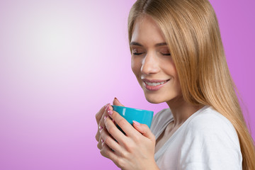 Young woman on studio background drinks coffee or tea