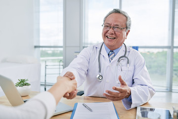 Vietnamese aged doctor greeting his patient before check-up