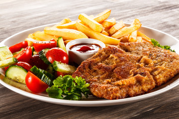 Fried pork chop, French fries and vegetable salad 