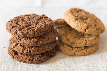 Cookies pile with chocolate chip on light textile background. Delicious morning snacks for breakfast, brunch and lunch. Appetizing, healthy, sweet, scrummy, and fast food.