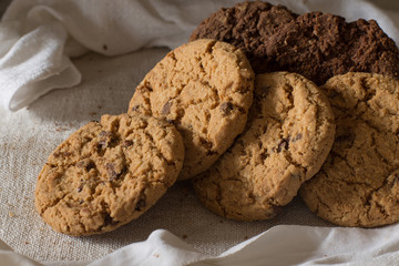 Cookies pile with chocolate chip on light textile background. Delicious morning snacks for breakfast, brunch and lunch. Appetizing, healthy, sweet, scrummy, and fast food.