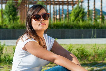 Beautiful woman wearing shades posing outside in park