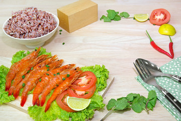 grilled shrimp on a wood tray with knife, fork,  vegetables,berr