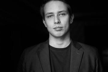 young man close up portrait, on black background