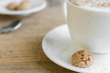 Cup of cafe latte with biscotti on wooden table