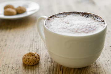 Cup of latte coffee with biscotti on wooden table