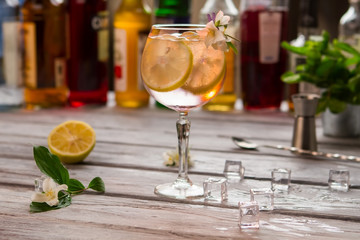 Beverage with slice of lemon. Wineglass decorated with flower. Juicy citrus fruit and ice. Refreshing taste of tom collins.