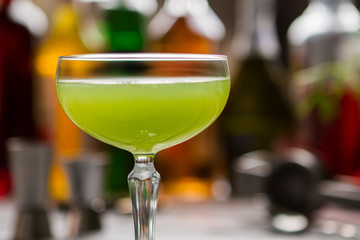 Green cocktail in glass. Coupe glass with bright liquid. Delicious drink made by bartender. Kiwi daiquiri with fresh juice.