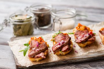 Small toasts with meat. Herb and mixture of vegetables. Simple dish from italian cuisine. Bruschetta cooked at home.