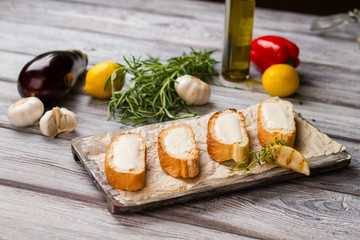 Baguette slices with butter. Piece of grilled lemon. Сrispy toasts and thyme. How to prepare appetizing meal.