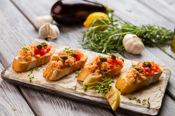 Grilled toasts with fish meat. Lemon slice and small capers. Bruschetta with chopped salmon. Traditional italian appetizer.