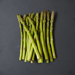 A pile of asparagus spears on a rustic slate background