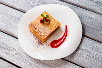 Dessert with sauce and berries. Mint leaves and chocolate crumbs. Top view of fresh millefeuille. Table in french cafe.