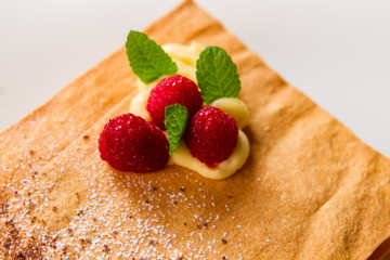 Raspberries and leaves of mint. Pastry with white powder. Simple recipe of crispy cake. Sweeten up your life.