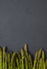Asparagus spears on a rustic slate background forming a vegetable themed page border