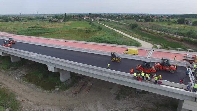 Aerial view on workers with heavy machines working on bridge reconstruction.
