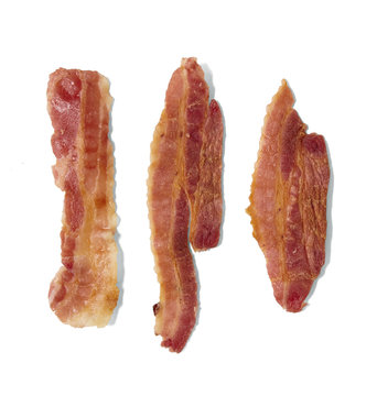 Individual strips of cooked streaky bacon isolated on a white background