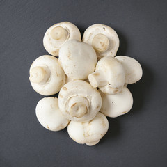 A pile of white closed cup mushrooms on a rustic slate background