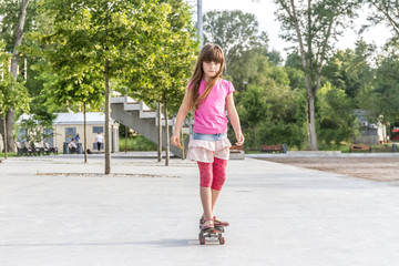 outdoor portrait of young smiling teenager girl riding skateboar