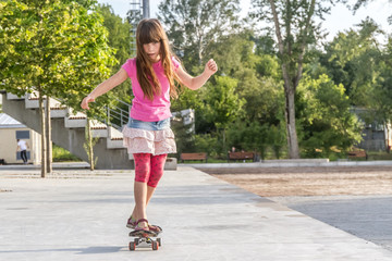 outdoor portrait of young smiling teenager girl riding skateboar