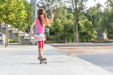 outdoor portrait of young smiling teenager girl riding skateboar