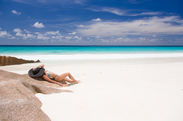 Fototapeta na wymiar Beautiful woman lays on the sandy beach of Seychelles