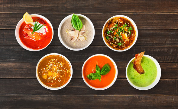 Variety of soups at brown wood, top view