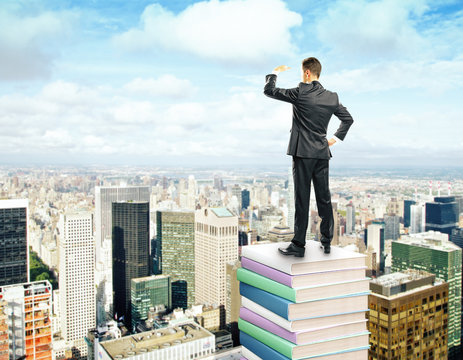 businessman standing on stack of books