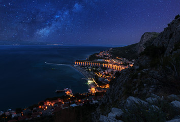 Fototapeta premium Aerial night view - Milky way over the town Omis and Adriatic coast of Mediterranean Sea, Dalmatia, Croatia
