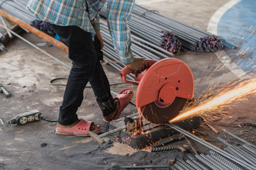 Construction builder worker with grinder machine cutting metal reinforcement rebar rods at building...