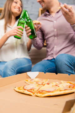 Happy couple in love spending holiday with pizza and beer