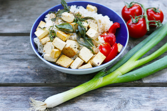 Veganes, vegetarische Mittagessen, Reis mit gebratenem Tofu in Kräuteröl, Salbei und Thymian mit frischen Tomaten