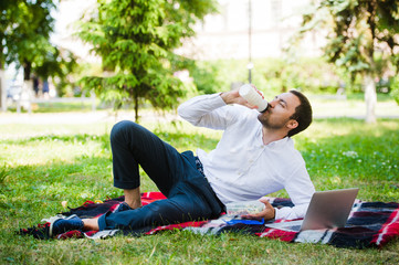 Young and attractive man relaxes in the park at lunch time