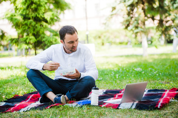Young and attractive man relaxes in the park at lunch time
