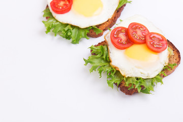 Two homemade sandwiches with egg, lettuce and tomato on a crispy slice of rye bread on a white wooden table. Space for text