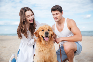 Young stylish couple in love sitting playing with dog