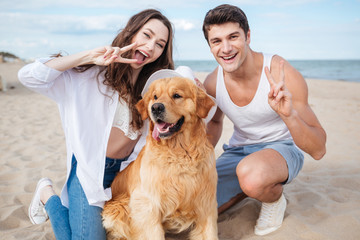 Young stylish beautiful couple in love sitting playing with dog