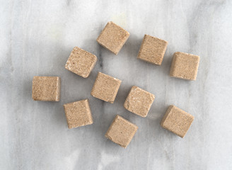 Beef flavored bouillon cubes on a gray marble cutting board.