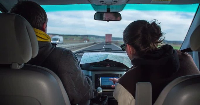 A guy in the passanger seat is tying the name of the street and the city into garmin. Three men are travelling to a new place for work. Close-up shot.
