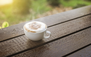 hot coffee in the morning on wood table with blurred garden in background,selective focus,filtered...