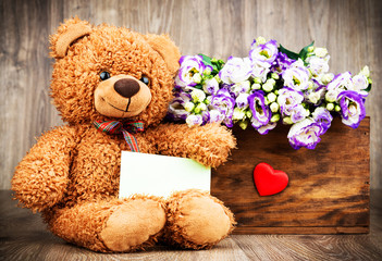 Eustoma flowers in the box and a teddy bear on wooden background