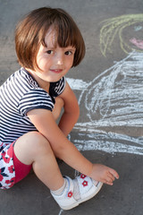Little girl drawing on the asfalt close-up