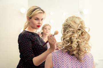 Professional makeup artist is preparing glamour model makeup at