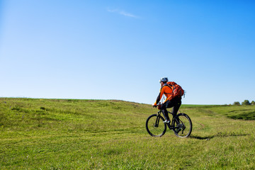 Fototapeta na wymiar Young man cycling on a rural road through green meadow