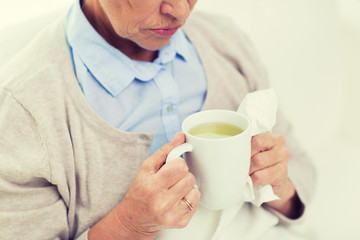 close up of sick senior woman drinking tea at home