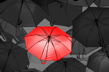 Red umbrella in black and white umbrellas