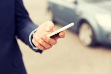close up of man hand with smartphone and car
