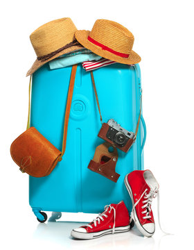 The blue suitcase, sneakers, clothing, hat, and retro camera on white background.