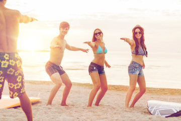 smiling friends in sunglasses with surfs on beach